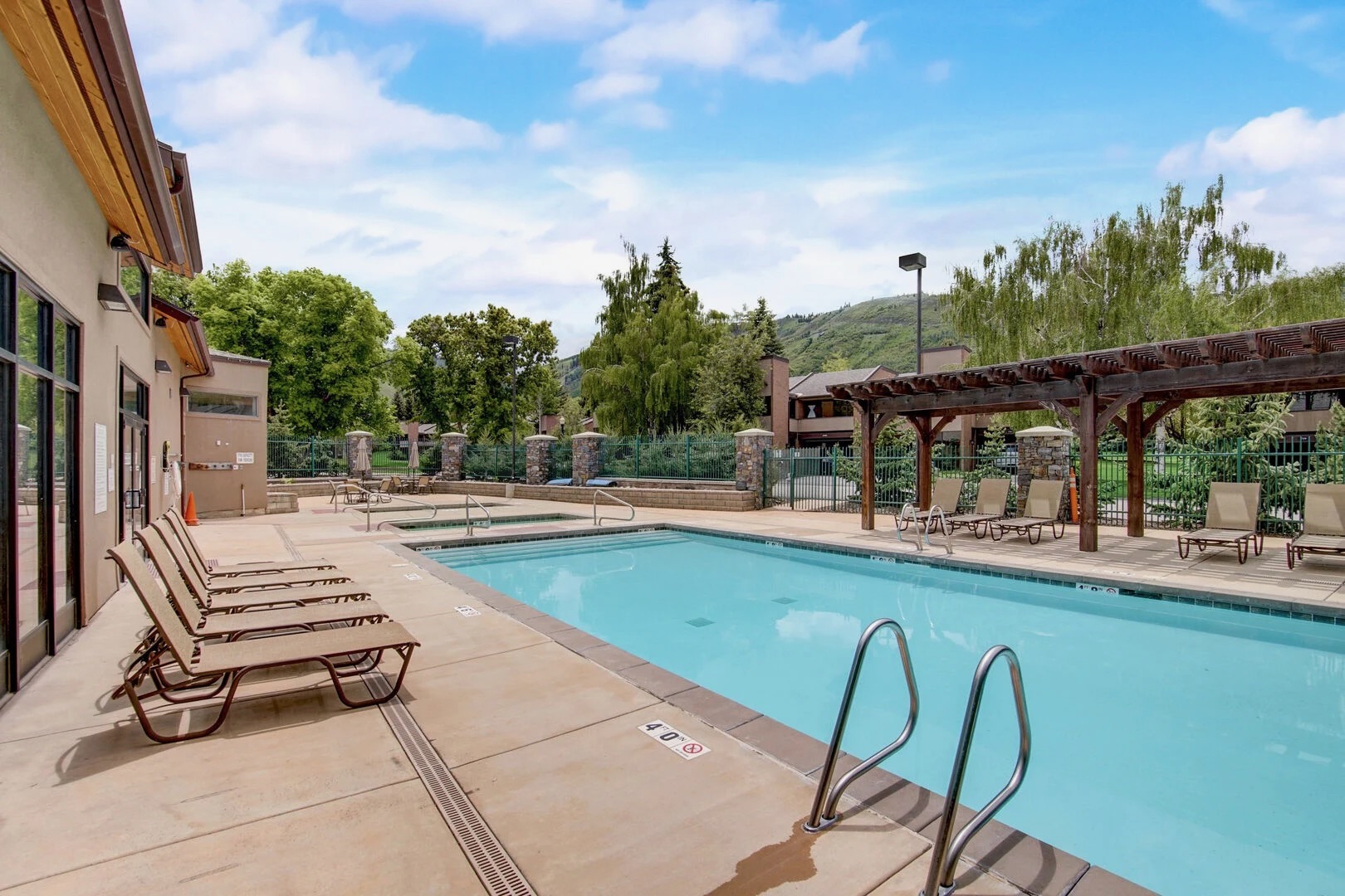 Park Avenue Condominiums community pool with lounge chairs, pergola, and mountain views